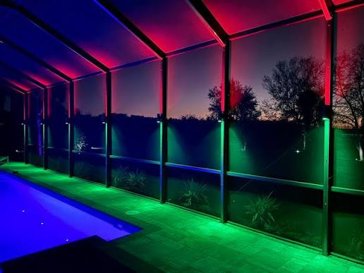 Dual-color permanent pool cage sconces on a Florida screen enclosure